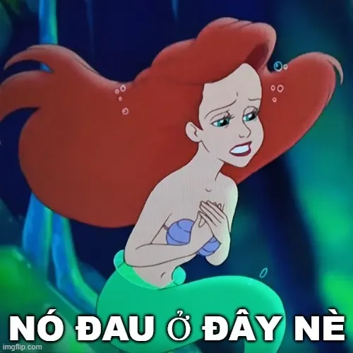 6 Nàng tiên cá tóc đỏ bồng bềnh ôm chặt hai tay trước ngực với biểu cảm ngạc nhiên pha chút tủi thân trong làn nước xanh.