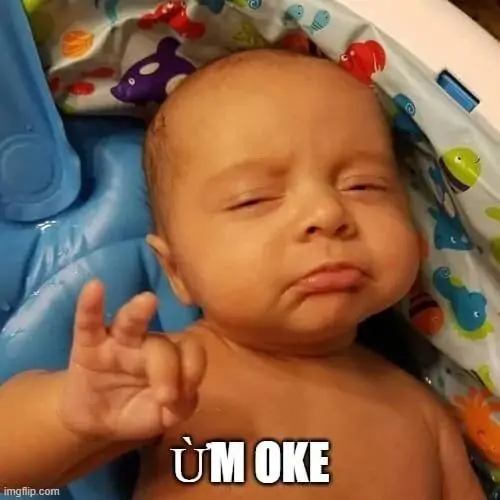 8 Hình chế đồng lòng em bé nằm trên thảm màu, bàn tay tạo vòng tròn bên chữ ÙM OKE nhìn vừa ngoan vừa buồn ngủ