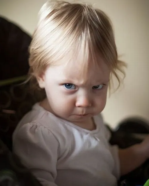 8 Ảnh troll đứa trẻ tóc vàng có đôi mắt sắc lẹm lườm trực diện vào ống kính với nụ cười gượng đầy vẻ hậm hực dọa dẫm.