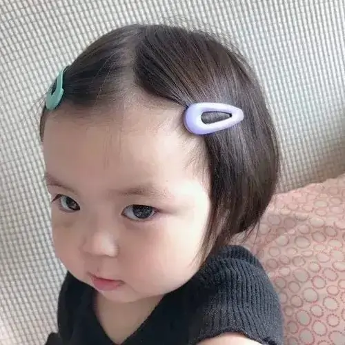 7 Ánh mắt liếc ngang của bé mặc áo đen, thêm hai chiếc kẹp tóc màu nhẹ, nhìn như đang âm thầm phán xét ai đó
