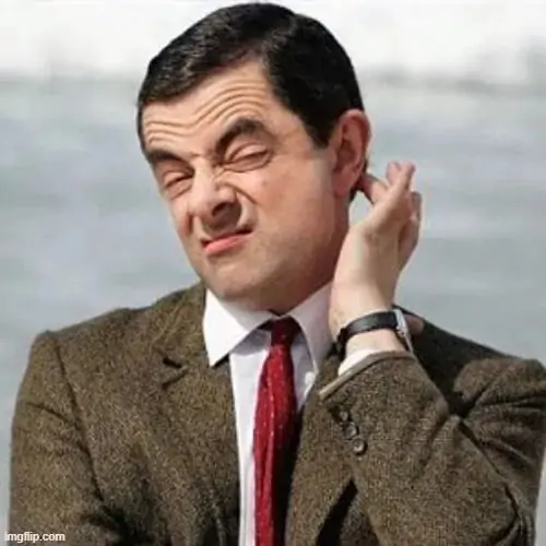 9 Nhân vật Mr Bean mặc vest nâu đưa tay gãi gáy với nụ cười trừ gượng gạo quen thuộc, tạo nên một ảnh chế lúng túng đầy tính thương hiệu.