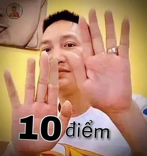18 Người đàn ông tóc ngắn giơ hai bàn tay sát camera, áo tối và chữ 10 điểm khiến khoảnh khắc tự tin hơi quá đà