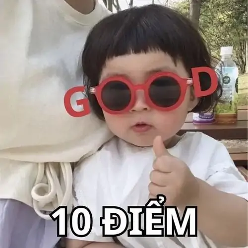 11 Bé đeo kính tròn đỏ, áo trắng cầm bảng GOOD trước mặt, chữ 10 điểm bên dưới làm dáng nghiêm túc hóa ra rất cưng