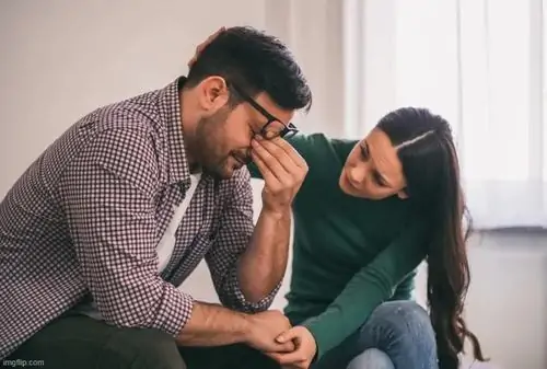 35 Người vợ ngồi bệt dưới sàn nhà nhẹ nhàng đặt tay lên lưng xoa dịu nỗi lòng cho anh chồng đang ôm mặt khóc vì quá áp lực.