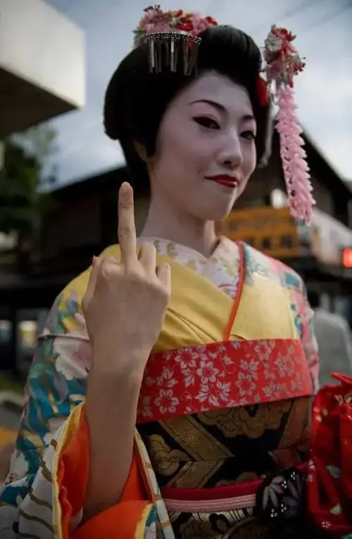 23 Cô gái mặc kimono đỏ đứng trước phông nền tối, biểu cảm nghiêm nhẹ làm cử chỉ tay trở nên vừa duyên vừa gắt