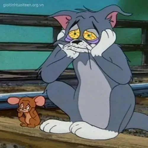 27 Tom ngồi trên ghế với hai tay ôm má, Jerry nhỏ bên dưới cũng nhìn theo, bối cảnh tối làm vẻ lo lắng thêm buồn cười