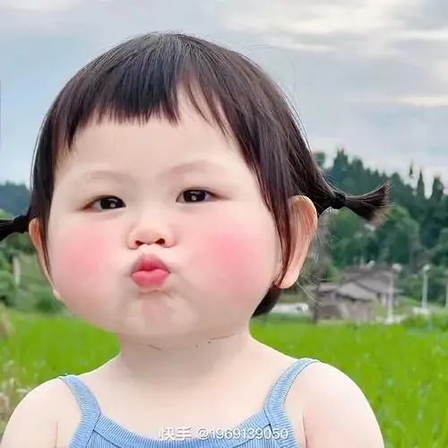 34 Giữa cánh đồng xanh, bé mặc yếm xanh chu môi hôn gió, hai bím tóc nhỏ làm vẻ mặt càng tròn xoe